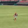 A baseball player pitching on a grass field in an empty stadium.