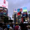 Dynamic city scene capturing the iconic Shibuya Crossing, bustling with people at dusk.