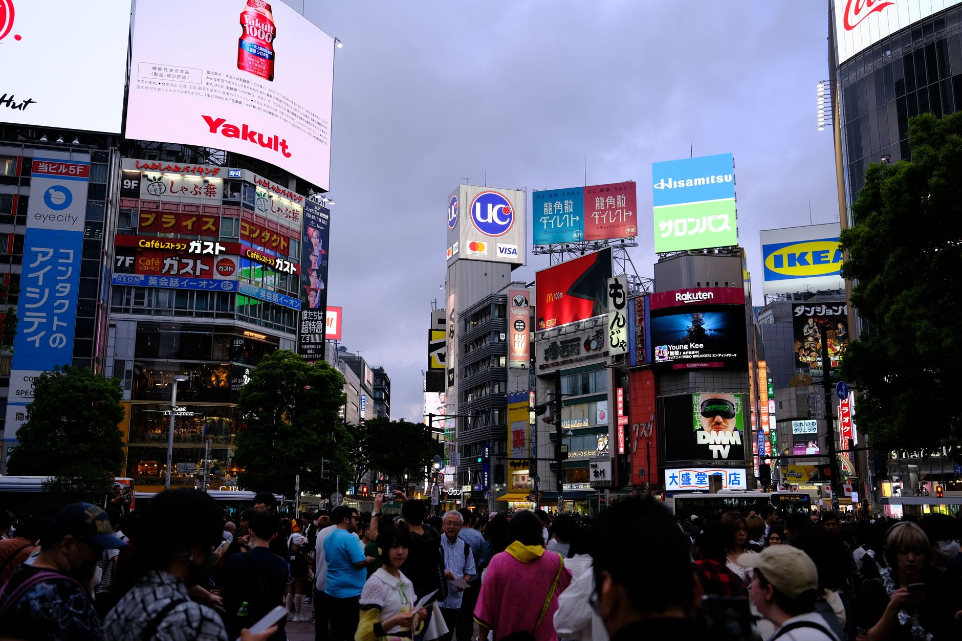 Dynamic city scene capturing the iconic Shibuya Crossing, bustling with people at dusk.