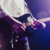Close-up of a musician passionately playing an electric guitar under stage lights.