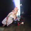 A female DJ with colorful tattoos and hair entertaining a lively nightclub audience.
