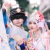 Cosplay enthusiasts in vibrant costumes posing outdoors with fans and peace signs.