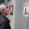 Senior man viewing photographs in an indoor art gallery exhibit.