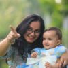 A candid outdoor photo of a mother and baby enjoying a first birthday celebration.