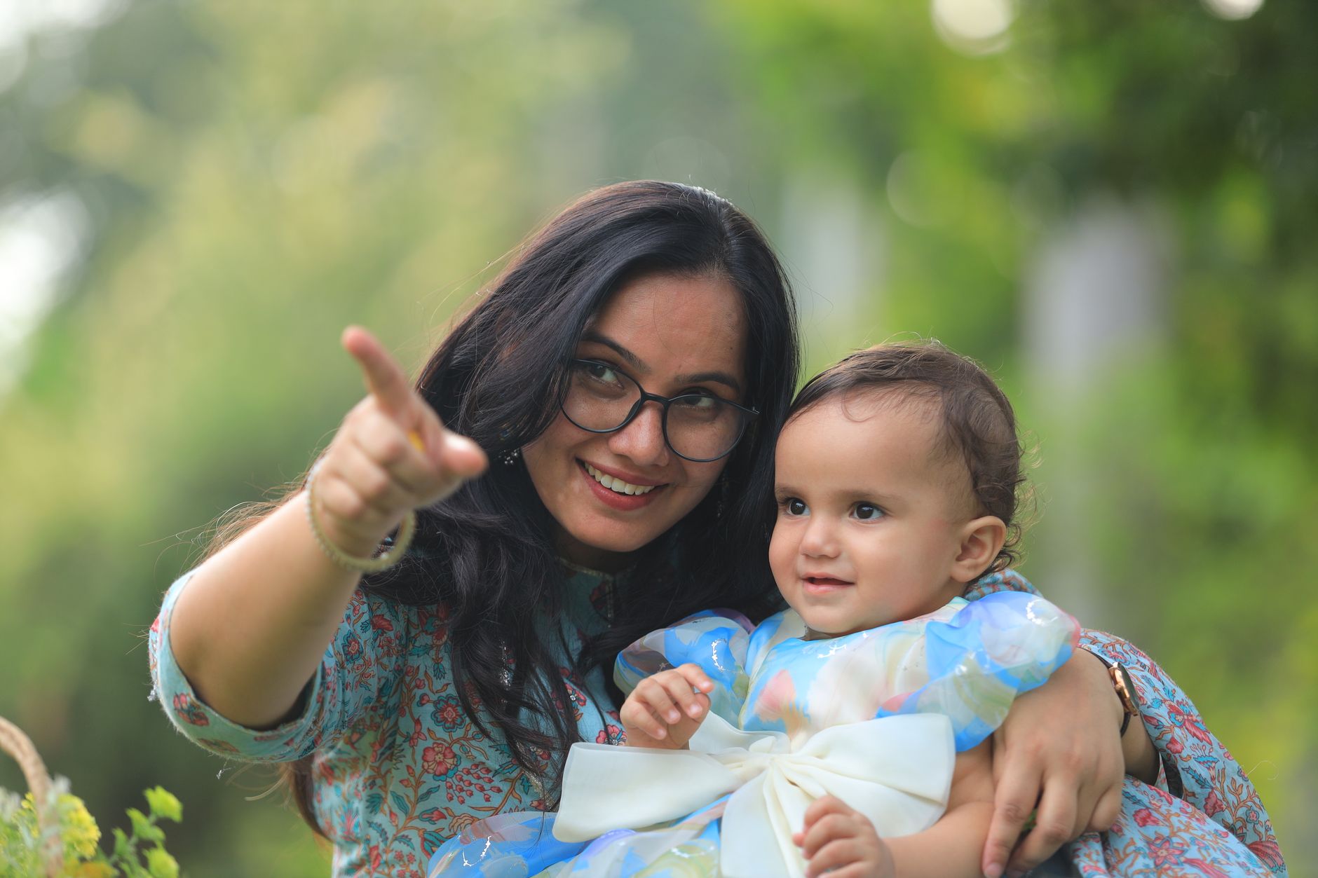 A candid outdoor photo of a mother and baby enjoying a first birthday celebration.
