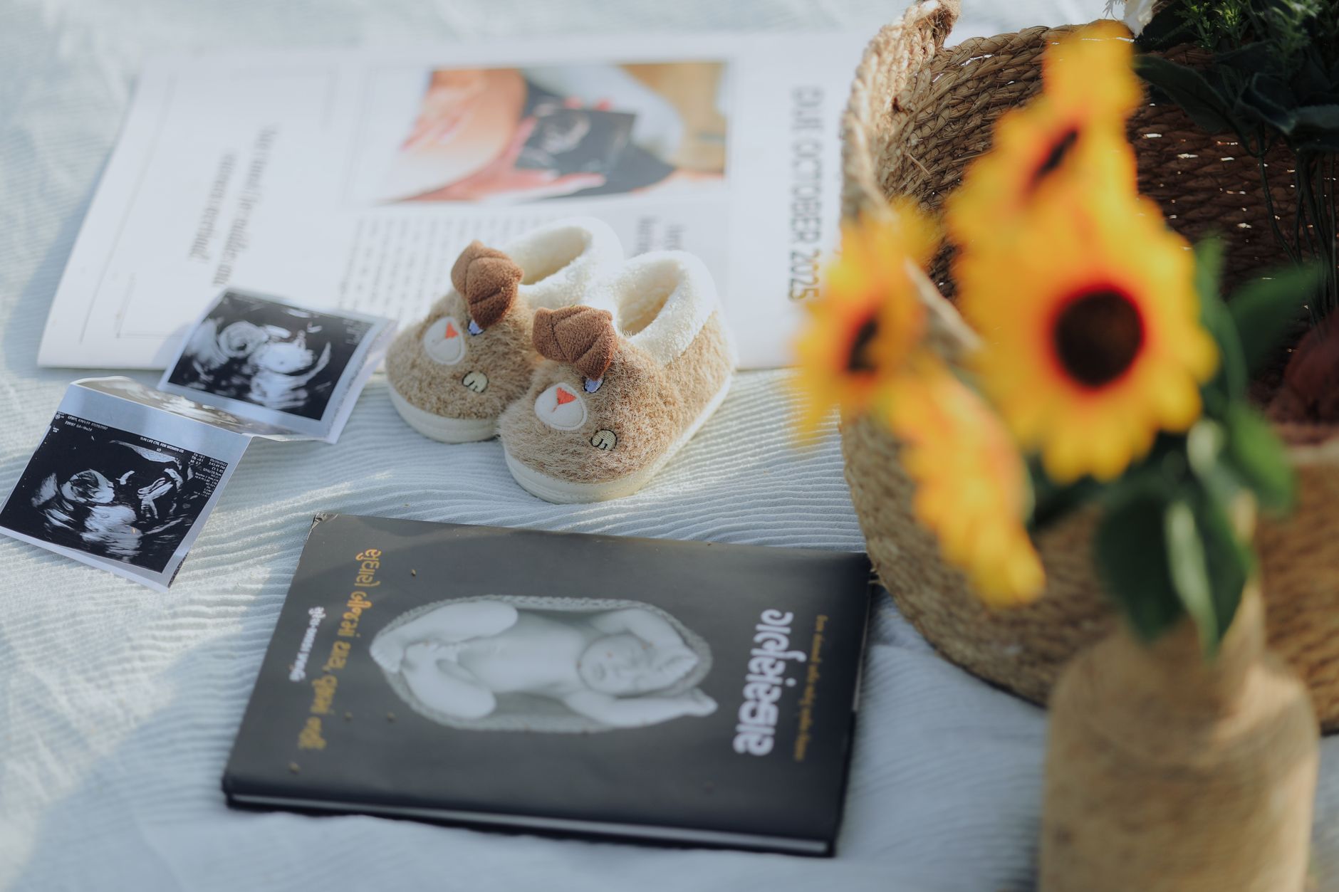 Flat lay of baby shoes, sonogram, and sunflowers, symbolizing pregnancy announcement.