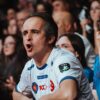Passionate fans in a crowd showing excitement at a sports event. Engaging atmosphere and team spirit.