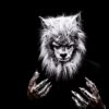 Striking portrait of an adult in a realistic werewolf costume with metallic claws against a black background.