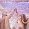 Capturing a blissful moment as a couple celebrates their Indian wedding with flower petals showered indoors.