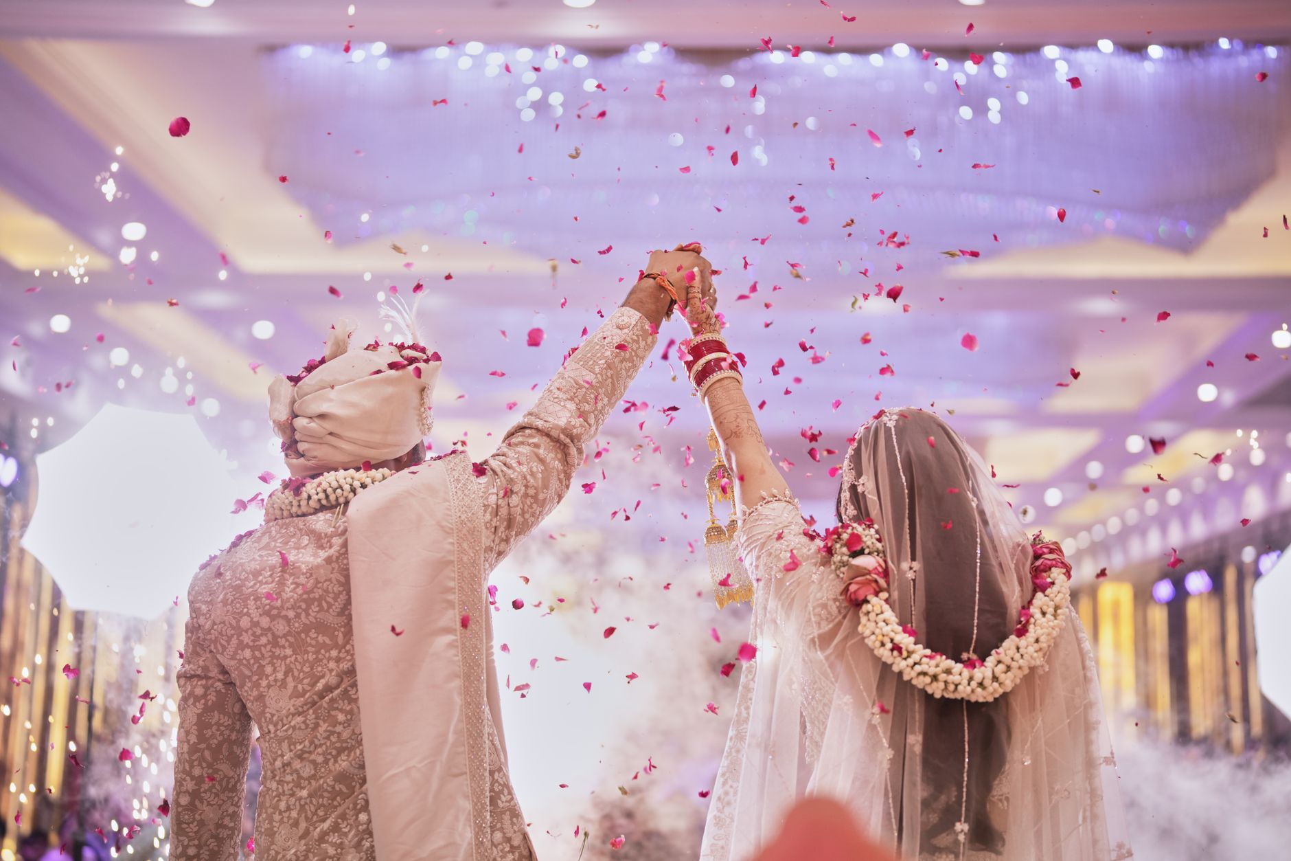 Capturing a blissful moment as a couple celebrates their Indian wedding with flower petals showered indoors.