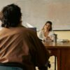 A teacher engages with a student in a university classroom setting, fostering learning.