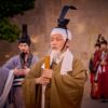 Men in traditional costumes perform a historical ceremony outdoors.