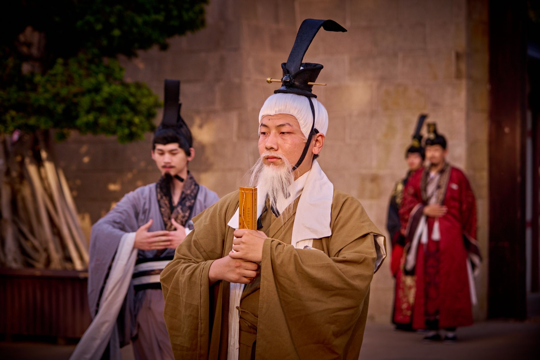 Men in traditional costumes perform a historical ceremony outdoors.