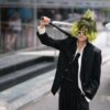A person in colorful cosplay holding a sword, standing confidently in an urban setting.
