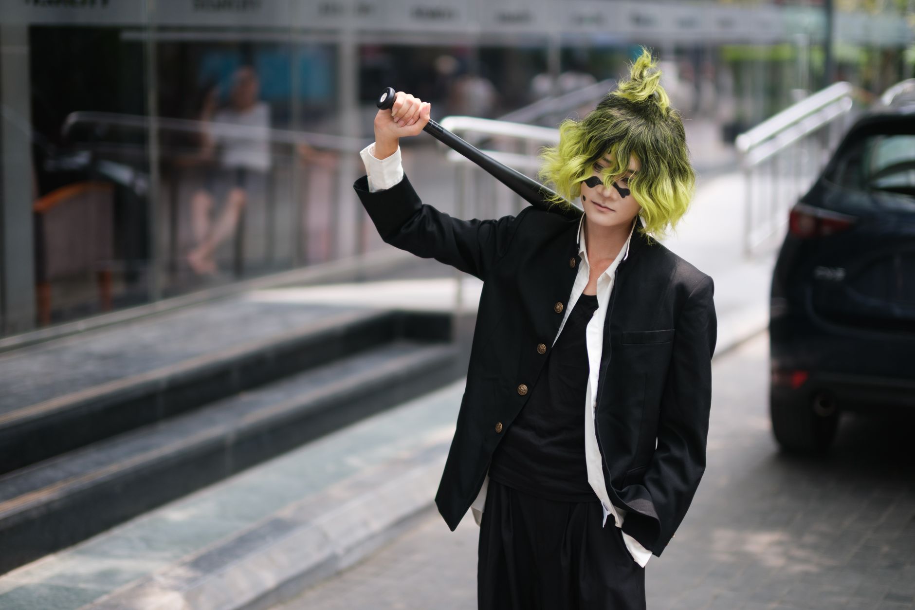 A person in colorful cosplay holding a sword, standing confidently in an urban setting.