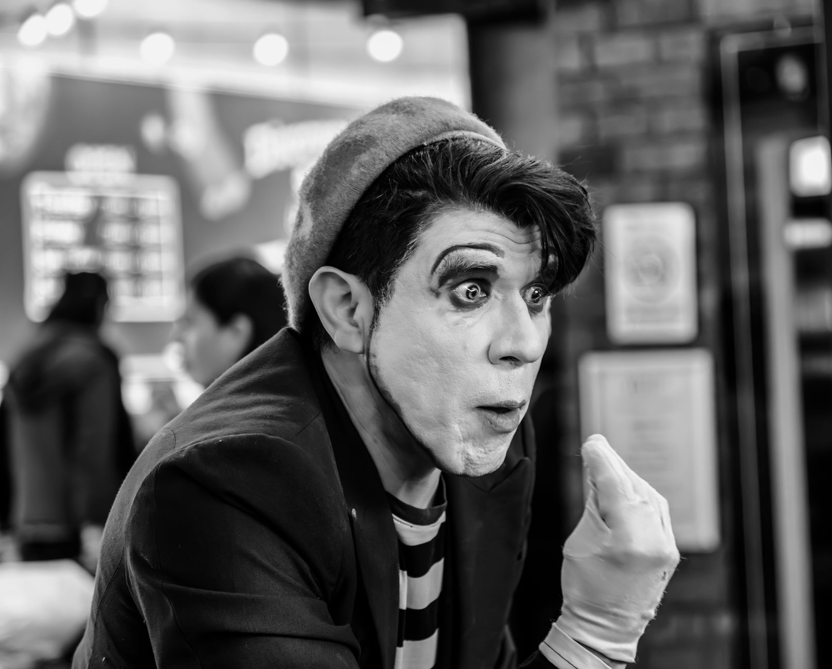 A captivating black and white portrait of a mime artist performing indoors, showcasing expressive facial expressions and makeup.