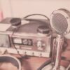 A classic vintage microphone and radio set with headphones displayed on a wooden table.