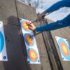 Close-up of archery target and archer in blue shirt during practice.