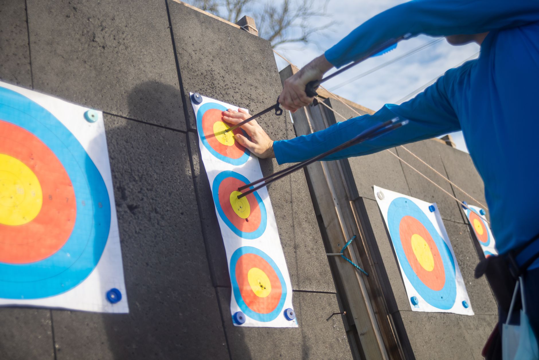 Close-up of archery target and archer in blue shirt during practice.