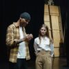 Two actors preparing for a scene during a theater rehearsal indoors.