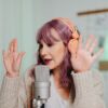 A woman podcasting in a studio setting with a microphone and headphones, gesturing expressively.