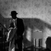 A black and white scene of a detective in a vintage interior, exuding mystery and intrigue.