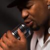 Close-up of a male singer passionately performing with a vintage microphone.