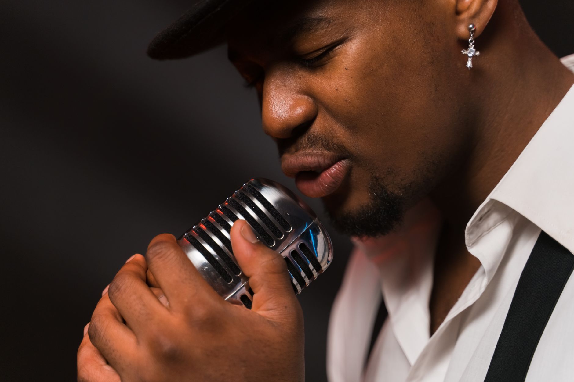 Close-up of a male singer passionately performing with a vintage microphone.
