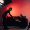 Behind-the-scenes view of a film crew in action, setting up a studio scene with lighting and equipment.