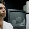 A thoughtful man is seen alongside vintage monitors, creating a reflective and nostalgic setting.