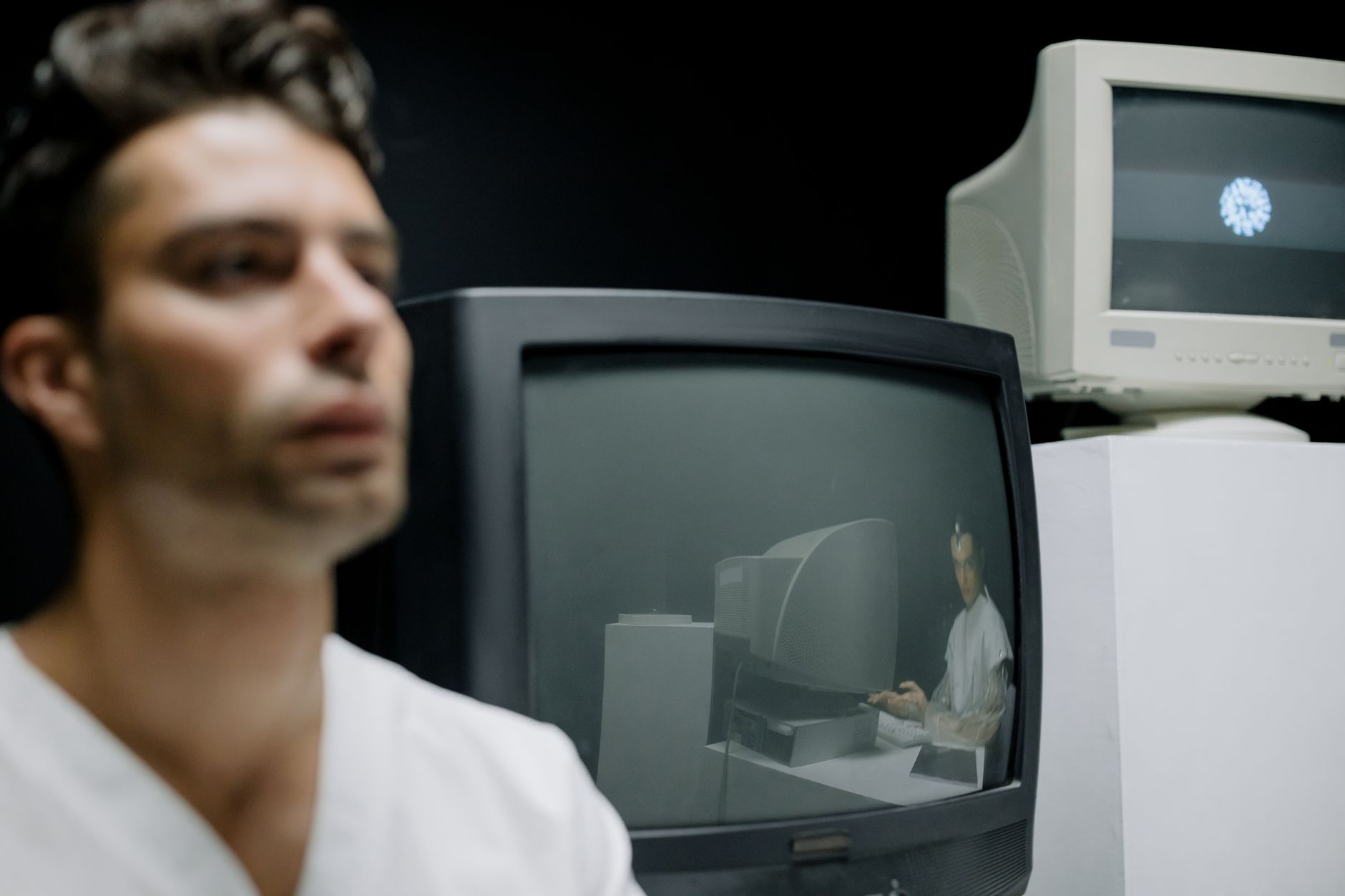 A thoughtful man is seen alongside vintage monitors, creating a reflective and nostalgic setting.