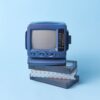 Vintage blue TV set featured atop VHS tapes on a pastel blue background, evoking a retro vibe.