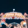 Brightly lit entrance to Pixar Pier at night, showcasing vivid carnival lights.